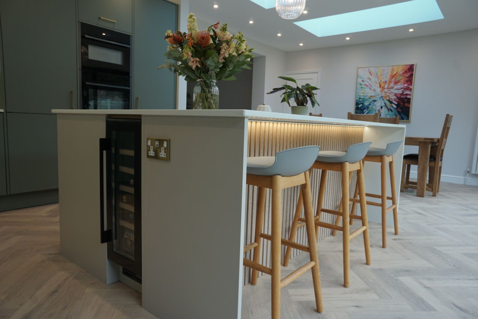 Breakfast bar with oak stools at an Avorio Trace quartz island with a built-in wine cooler