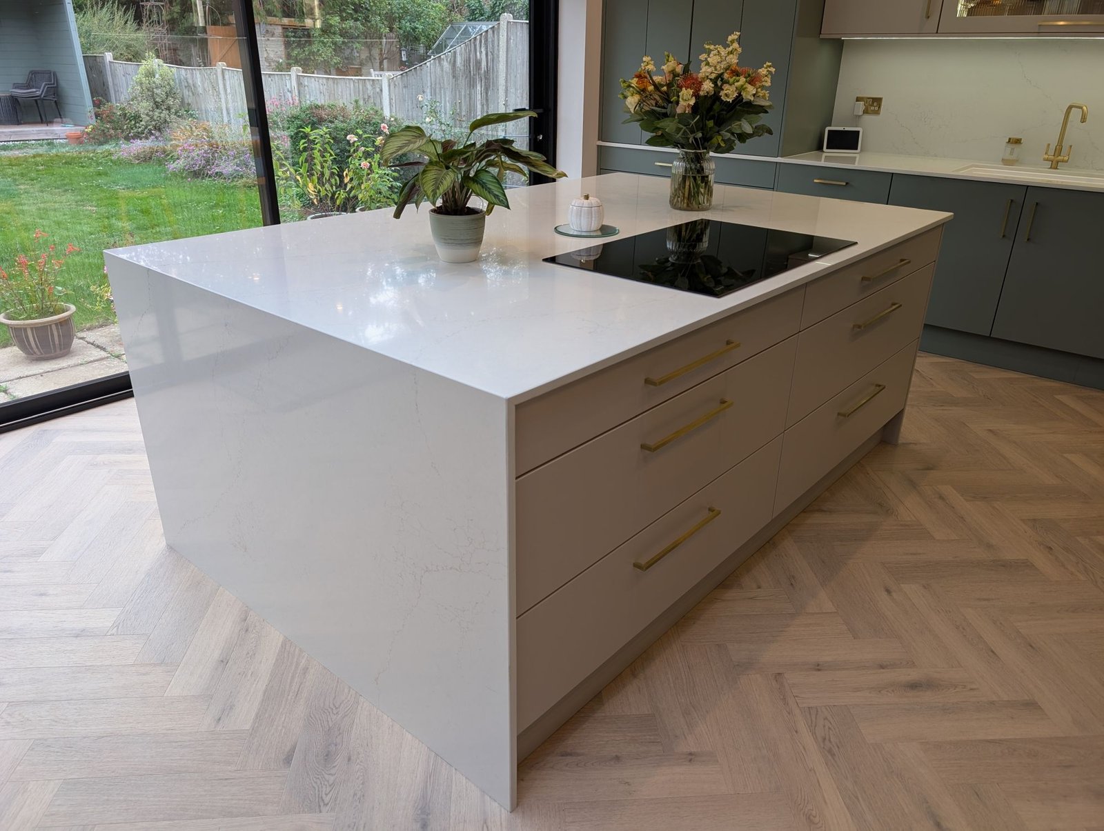 Island with an Avorio Trace quartz top running down one end as a waterfall, beside bifold doors
