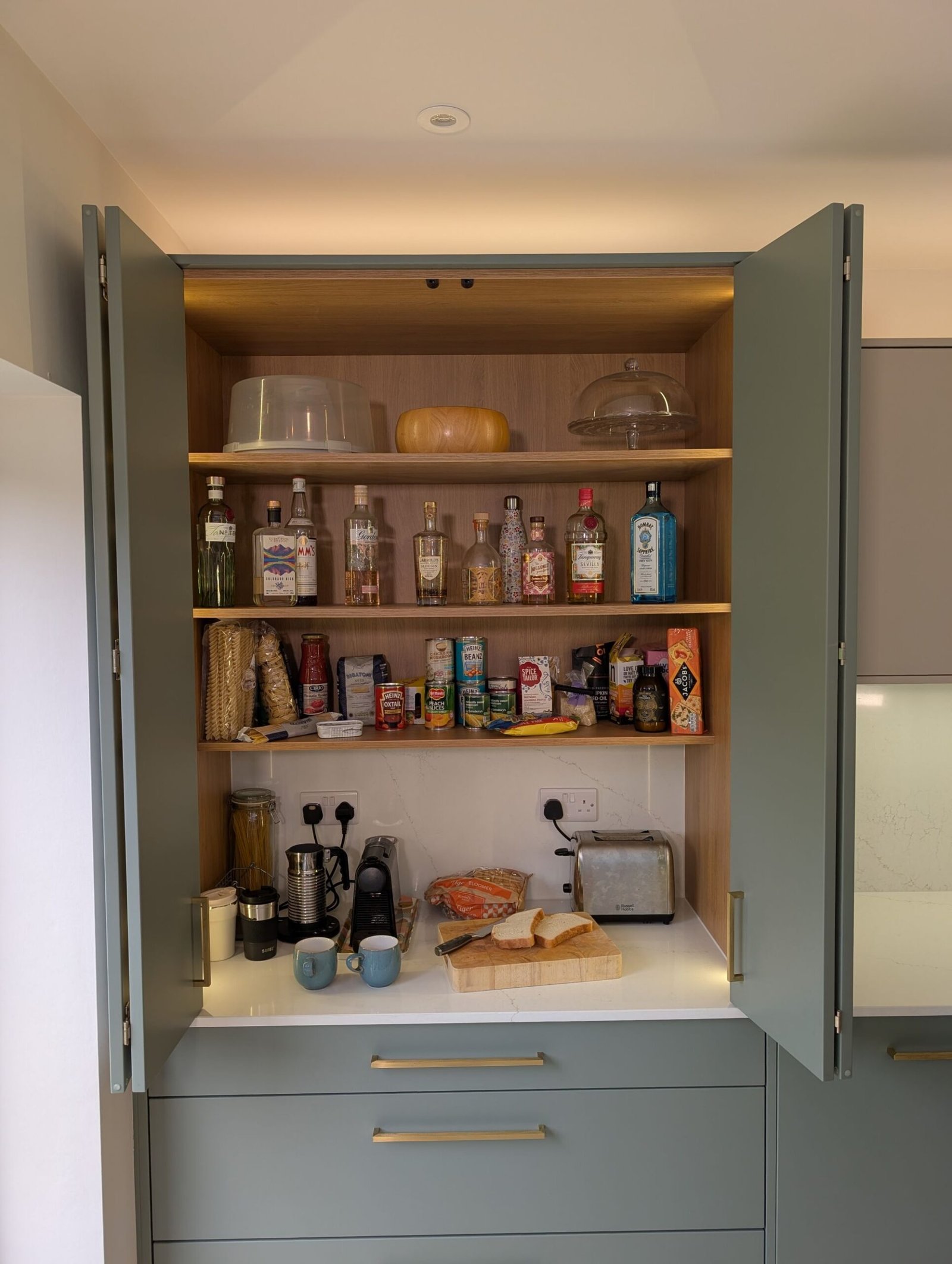Open Reed Green larder cupboard with oak shelves and an Avorio Trace quartz worktop inside