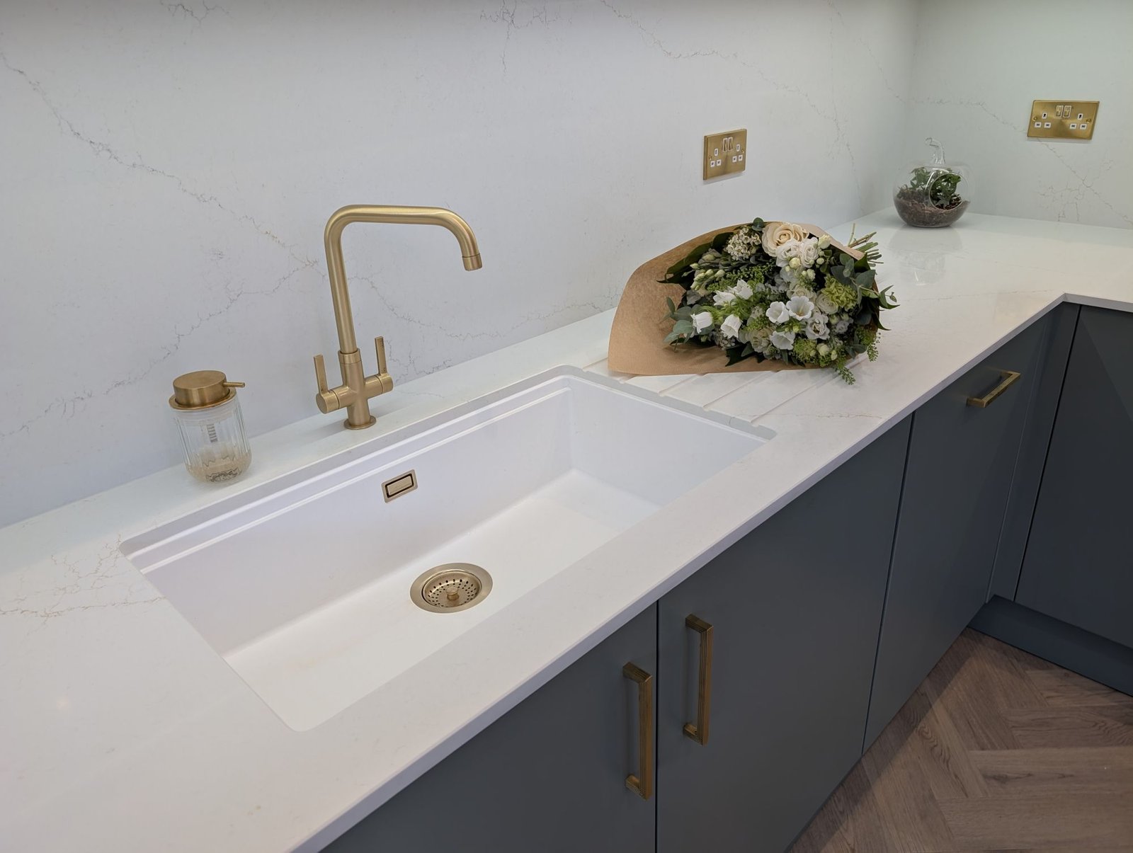 White undermount sink and brushed brass tap in an Avorio Trace quartz worktop with a full quartz splashback