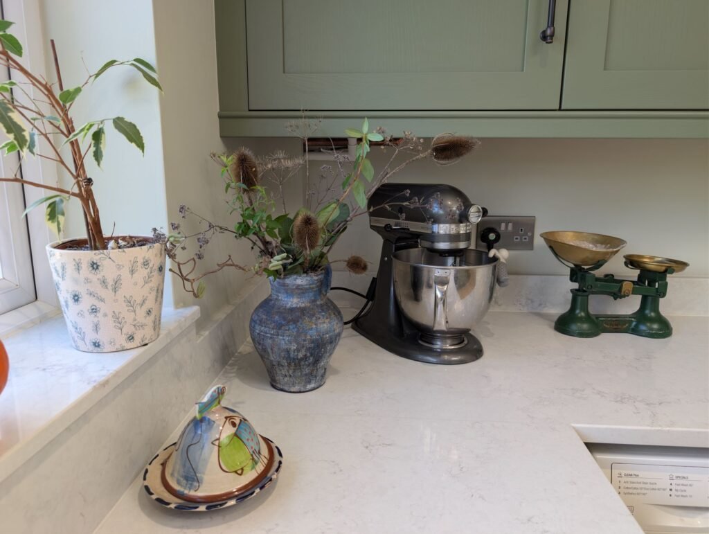 Chalk Mist quartz window sill and worktop corner with plants and a stand mixer under sage green wall units