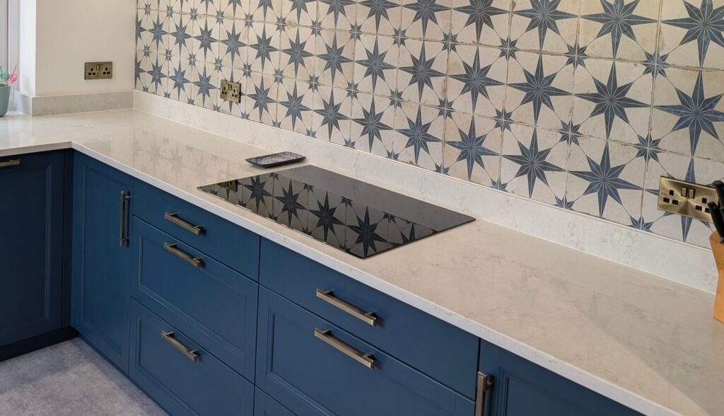 Chalk Mist quartz worktop and upstand on navy shaker units with an induction hob and star-pattern tiles