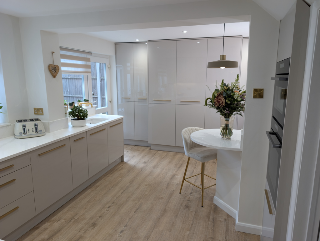 Gilded Vein quartz worktop run leading to tall gloss units and a teardrop quartz breakfast table