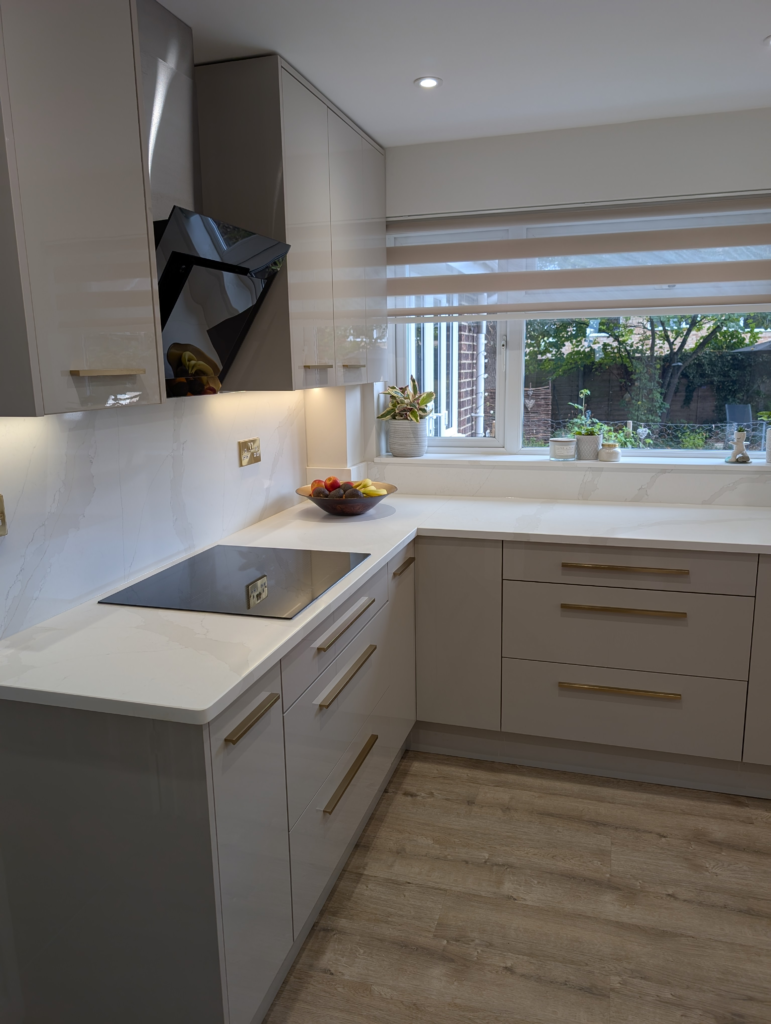 Corner of a gloss cashmere kitchen with Gilded Vein quartz worktop, splashback and window sill