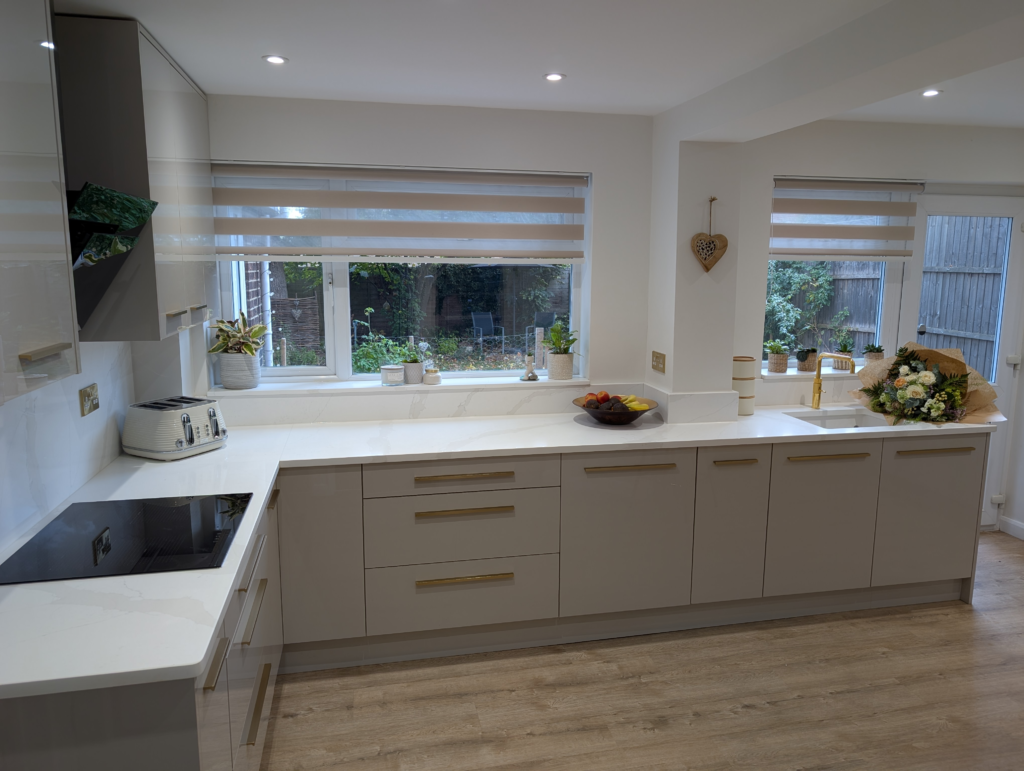 Long run of Gilded Vein quartz worktop under two windows, with quartz sills, a hob and a brass tap